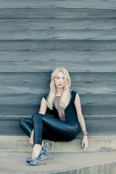 Блондинка сидит у деревянной стены — стоковое фото
