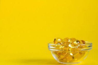 Omega 3 kapsüllü kase sarı arka planda, kopyalanmış alan, yan görünüm