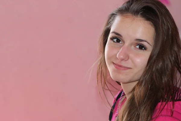 Pretty young girl on a pink background, long straight hair, cute smiling, teenager, brown eyes — Stock Photo, Image