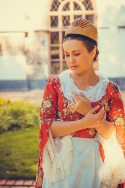 Esmer kadın portresi. Kırmızı tarihi Barok kıyafetler giymiş. Eski moda saç stili, açık havada. Orta sınıf ortaçağ elbisesi