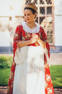 Esmer kadın portresi. Kırmızı tarihi Barok kıyafetler giymiş. Eski moda saç stili, açık havada. Orta sınıf ortaçağ elbisesi