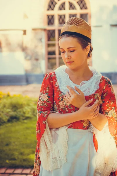 Esmer kadın portresi. Kırmızı tarihi Barok kıyafetler giymiş. Eski moda saç stili, açık havada. Orta sınıf ortaçağ elbisesi