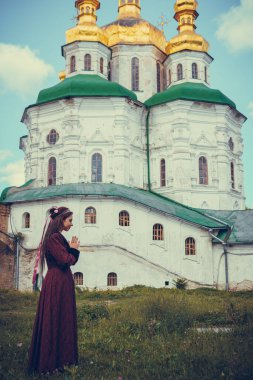 Dua eden esmer bir kadının portresi. Tarihi Barok giysileri içinde, açık havada. Orta sınıf ortaçağ elbisesi