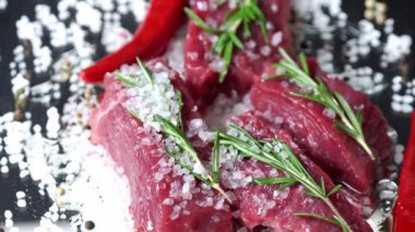 Biberiyeli çiğ organik et, baharatlar, tuz ve koyu arkaplanda dönen kırmızı biber. Barbekü için hazırlık