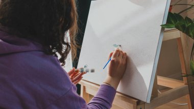 Yetişkin kadın resimlerini sayılarla, pastel renklerle, tuvale çiziyor. Boş zaman aktivitesi, hobi ve rahatlama kavramları