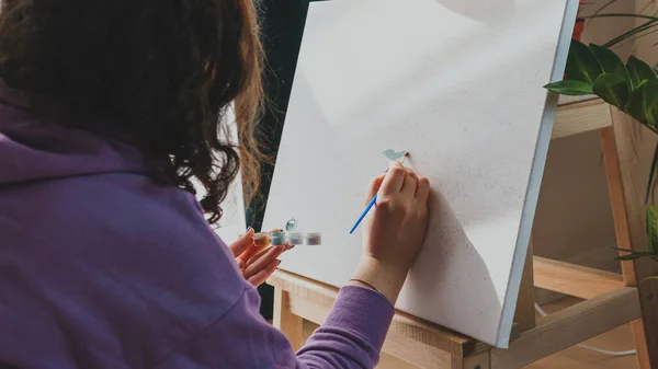Yetişkin kadın resimlerini sayılarla, pastel renklerle, tuvale çiziyor. Boş zaman aktivitesi, hobi ve rahatlama kavramları