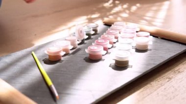 Yetişkin kadın resimlerini sayılarla, pastel renklerle, tuvale çiziyor. Boş zaman aktivitesi, hobi ve rahatlama kavramları
