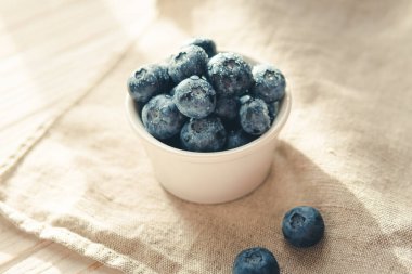 Freshly picked juicy blueberries in the bowl on wooden background, close up. Blueberries background. Concept of healthy nutrition, organic food. Vegan and vegetarian