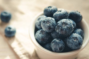 Freshly picked juicy blueberries in the bowl on wooden background, close up. Blueberries background. Concept of healthy nutrition, organic food. Vegan and vegetarian