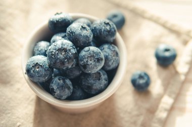 Freshly picked juicy blueberries in the bowl on wooden background, close up. Blueberries background. Concept of healthy nutrition, organic food. Vegan and vegetarian