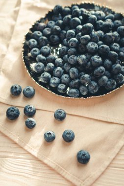Freshly picked juicy blueberries in the bowl on wooden background, close up. Blueberries background. Concept of healthy nutrition, organic food. Vegan and vegetarian