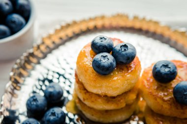 Homemade cheesecake with freshly picked juicy blueberries in the plate on wooden background, close up. Blueberries background. Concept of healthy nutrition, organic food, breakfast