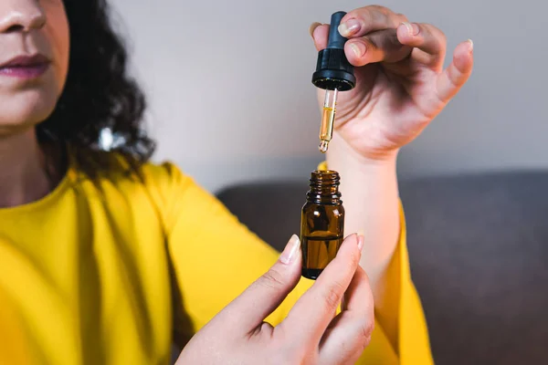 Tıbbi kenevir yağı kullanan ve elinde tutan yetişkin bir kadın. CBD 'de. Bitkisel ve alternatif tıp kavramı