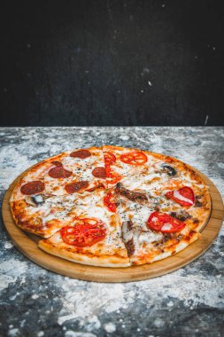 Soyut koyu arkaplanda buğday unuyla İtalyan pizzası dilimleri.