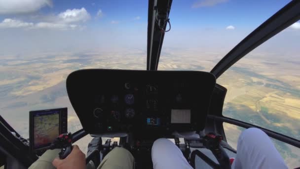 Binnenaanzicht van een helikopter in vlucht met piloot en man die een helikopter bestuurt op een zonnige dag. — Stockvideo