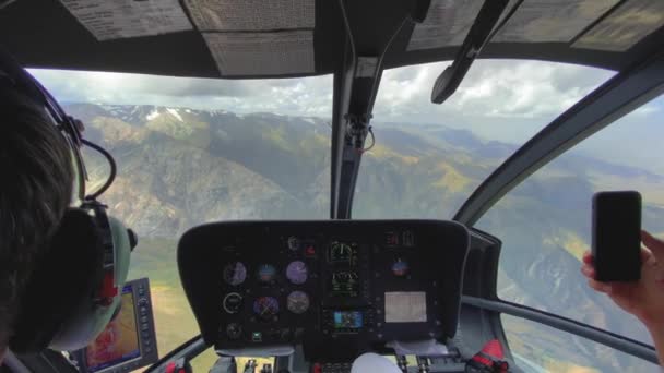 Widok z tyłu pilota i kabiny pilota lecących helikopterem nad wysokimi górami. — Wideo stockowe