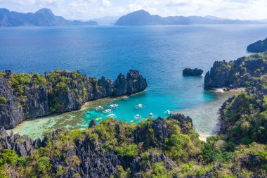Gök mavisi deniz ve turist teknelerinin El Nido, Palawan, Filipinler 'deki güzel büyük ve küçük lagünlerin etrafını gösteren hava aracı görüntüsü..
