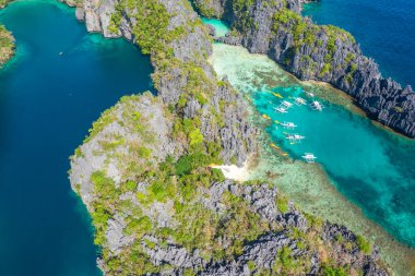 Gök mavisi deniz ve turist teknelerinin El Nido, Palawan, Filipinler 'deki güzel büyük ve küçük lagünlerin etrafını gösteren hava aracı görüntüsü..