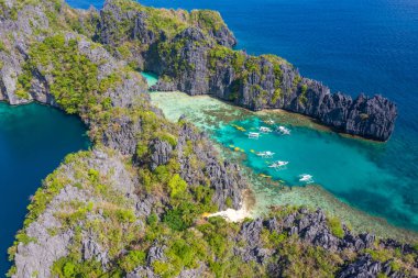 Gök mavisi deniz ve turist teknelerinin El Nido, Palawan, Filipinler 'deki güzel büyük ve küçük lagünlerin etrafını gösteren hava aracı görüntüsü..