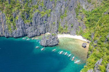 Tropikal mercan resifleri ve uzak kumlu Saklı Kumsal, El Nido, Palawan, Filipinler üzerindeki teknelerin insansız hava aracı görüntüsü.