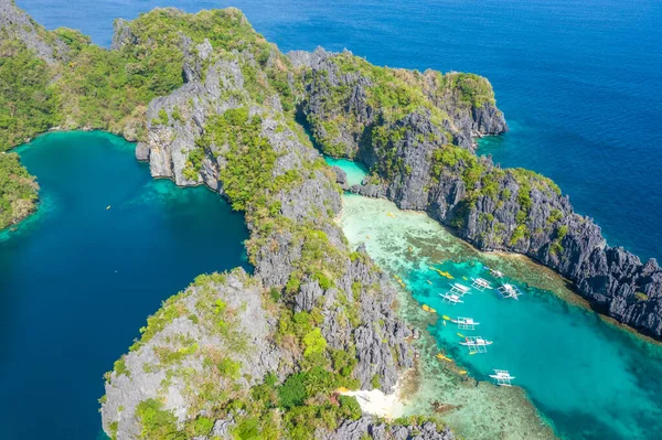 Gök mavisi deniz ve turist teknelerinin El Nido, Palawan, Filipinler 'deki güzel büyük ve küçük lagünlerin etrafını gösteren hava aracı görüntüsü..