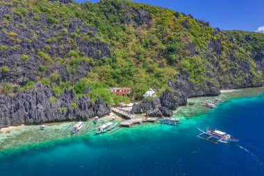 Güzel mercan kayalıkları, tekneler ve Matinloc Adası 'nda açık bir okyanus Bacuit Takımadası, El Nido, Palawan, Filipinler. Hava aracı görünümü