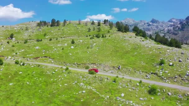 15 Temmuz 2021 - Karadağ. Karadağ 'ın Komovi kentindeki güzel dağlarda kırmızı arabalı hava manzaralı yol manzarası. Arabayla seyahat kavramı. — Stok video