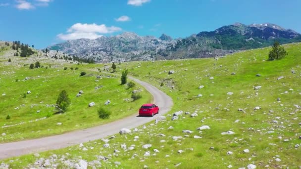 Luchtfoto van weg met rode auto in prachtige bergen in Komovi. 15 juli 2021 - Montenegro. — Stockvideo
