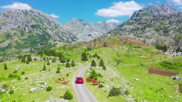 コモヴィ、モンテネグロの道路や赤い車と美しい山の風景。車での旅行のコンセプト旅行. — ストック動画