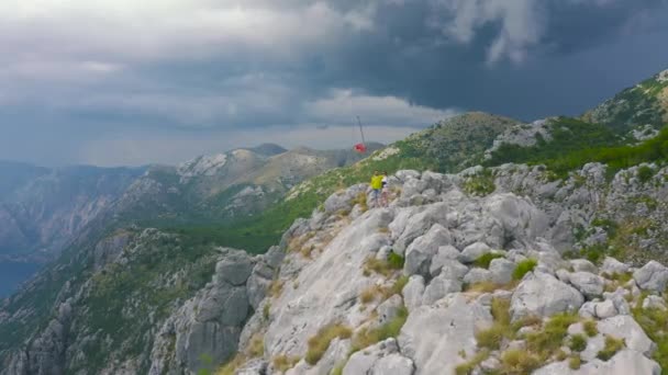 Young travelers standing on a mountain peak and looking on sea of Kotor bay, Montenegro. Aerial drone view. Lifestyle and travel concept. — Vídeo de Stock