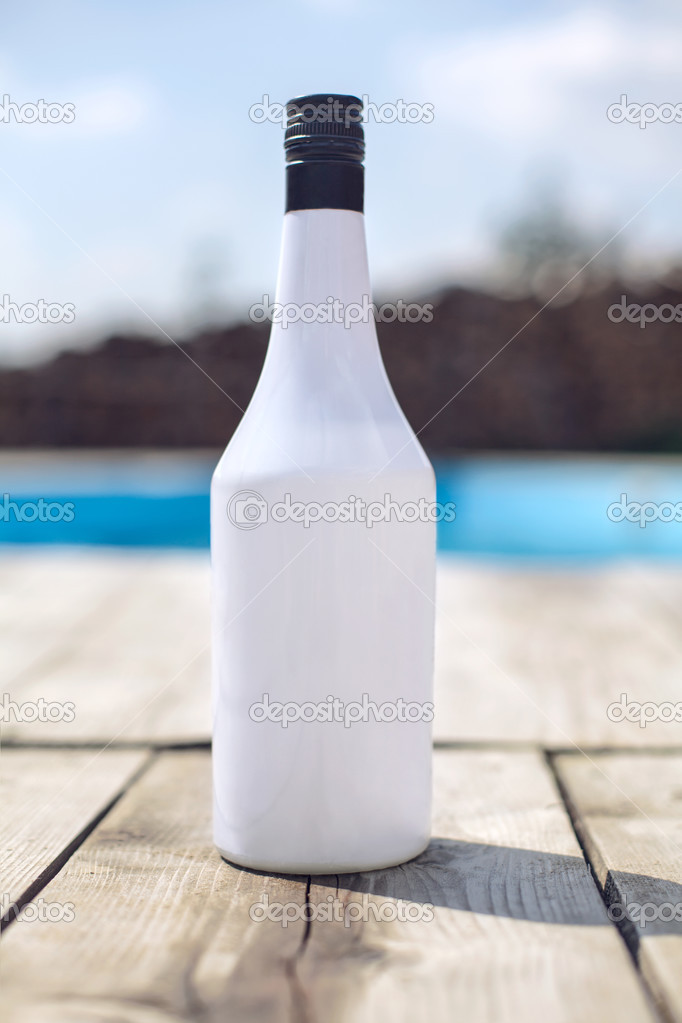 Vacation white alcohol bottle near swimming pool