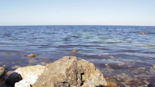 Spokojne błękitne morze z kamieniem na pierwszym planie. Niebieska powierzchnia fal wodnych, piękne tło — Wideo stockowe
