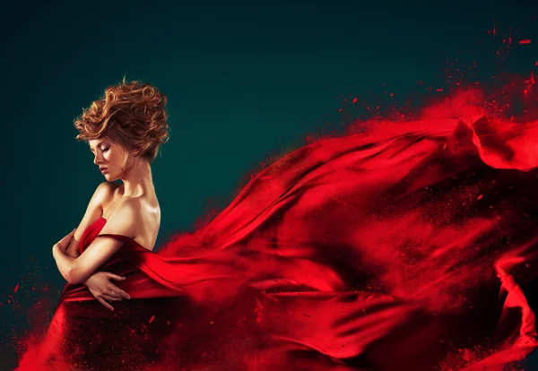 Mujer en rojo soplando vestido rojo volador disolviéndose en salpicadura Fotos de stock