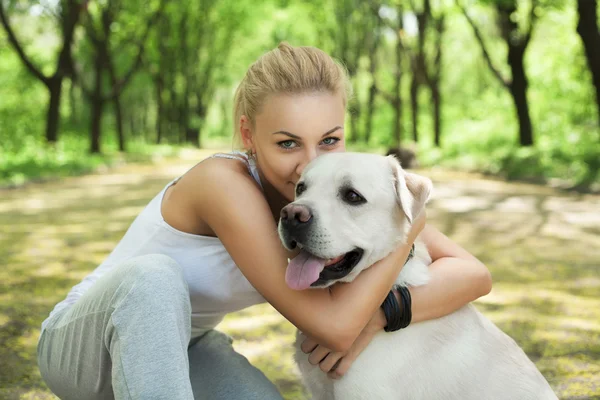 魅力的なブロンドの若い女の子、公園で犬と遊んで ストックフォト