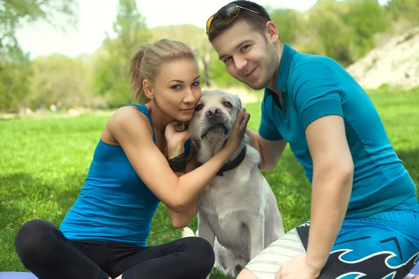 Jovem casal com um cão no parque — Fotografia de Stock