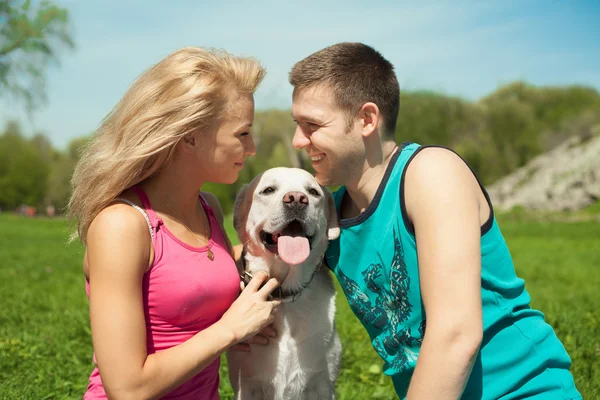 Joven pareja deportiva con un perro en el parque — Foto de Stock