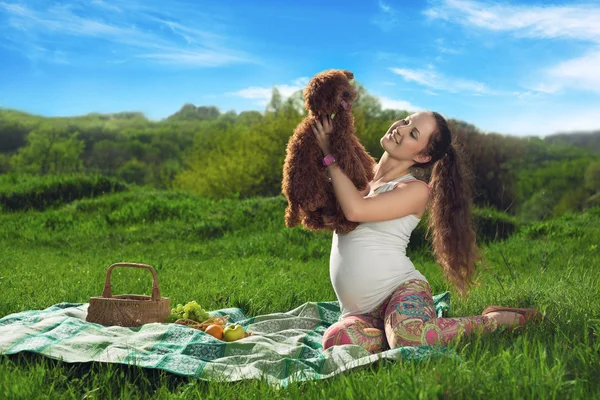 Красивая беременная женщина отдыхает в парке с маленькой собачкой — стоковое фото