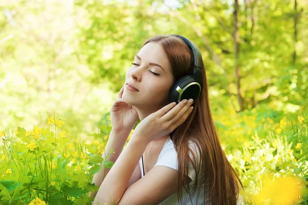 Menina feliz com fones de ouvido desfrutando da natureza no dia ensolarado . — Fotografia de Stock