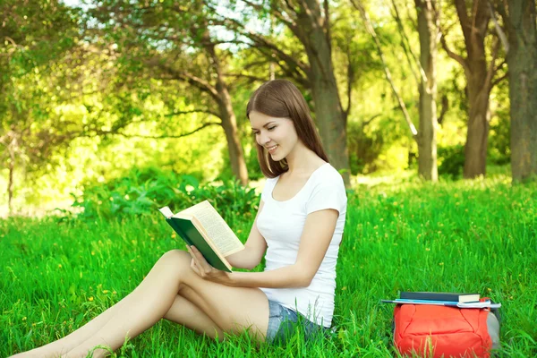 Портрет красивої молодої дівчини, що читає книгу в парку на с — стокове фото