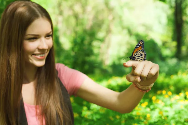 Mariposa sentada en el dedo de una joven en el parque Imagen de archivo
