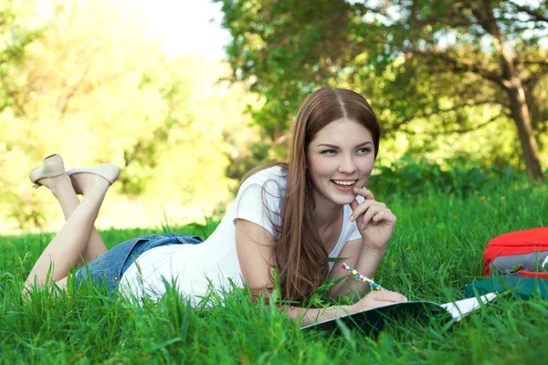 Joven estudiante universitaria con libro y bolso estudiando en un parque —  Fotos de Stock