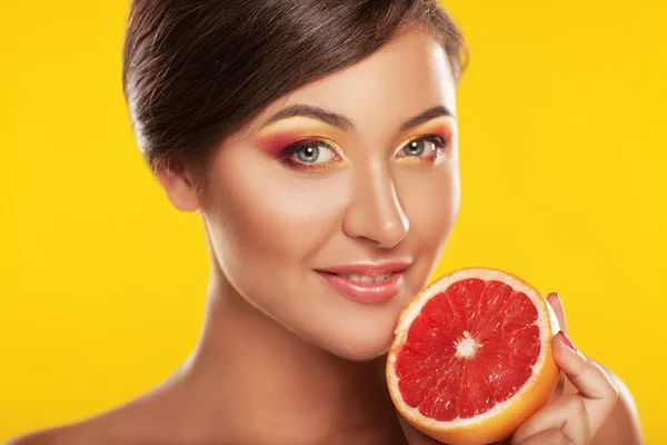 Close up female face with fresh grapefruit in her hands, over ye — Stock Photo, Image