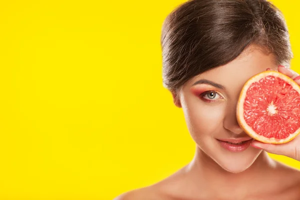 Vacker ung kvinna med ljusa make-up, hålla grapefrukt, o — Stockfoto