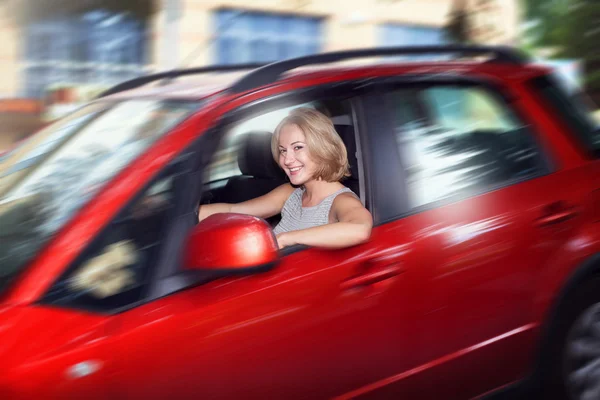 Attractive blonde young woman driving her red car and look out o — Stock Photo, Image