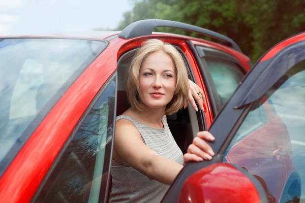 Portret van jonge mooie blonde vrouw in de rode auto — Stockfoto