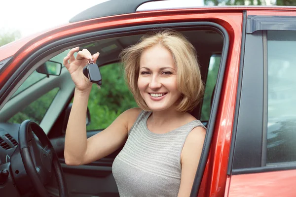 Portrait of happy beautiful blonde woman with car key, sitting i — Stock Photo, Image
