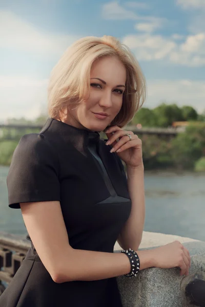 Portrait of a pretty blonde girl standing at the bridge of the r — Stock Photo, Image