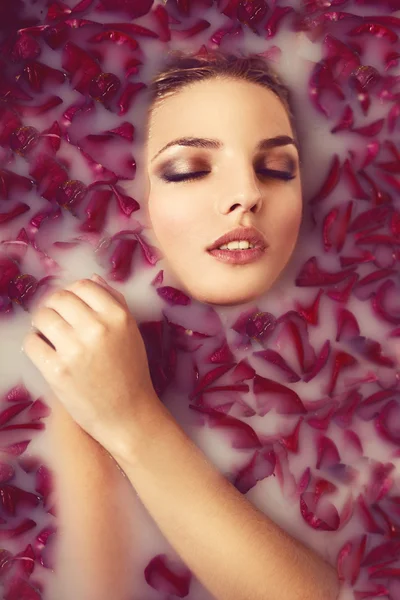 Chica toma un baño con leche y pétalos de rosa — Foto de Stock