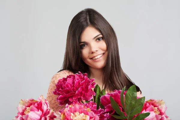 Frau lächelt und hält Blumen in der Hand — Stockfoto