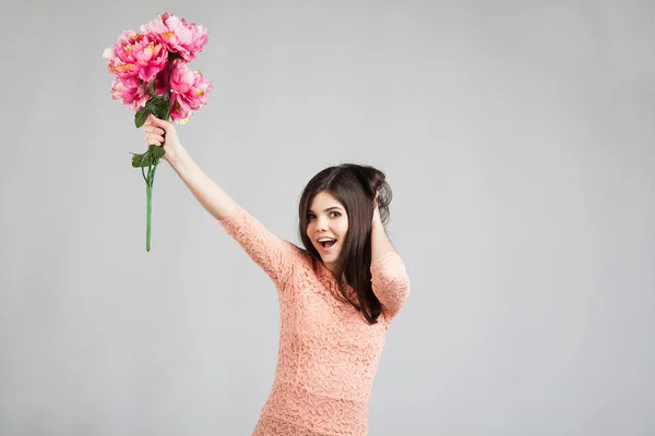 Frau lächelt und hält Blumen in der Hand — Stockfoto